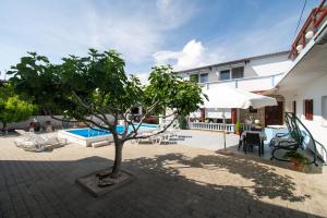 une cour avec un arbre et une piscine dans l'établissement Apartments Denis, à Tribunj