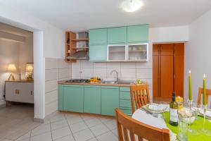 una cucina con tavolo e una cucina con armadi blu di Apartments Lenka a Orebić (Sabbioncello)