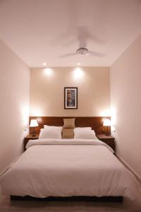 - une chambre avec un grand lit blanc et deux lampes dans l'établissement The Elet Signature Boutique Hotel, à Karachi