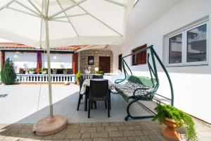 une terrasse avec un parasol, une table et des chaises dans l'établissement Apartments Denis, à Tribunj