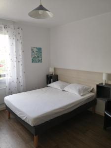 une chambre avec un lit avec des draps blancs et une fenêtre dans l'établissement Appartement meublé 1 étoile - Tourisme tout confort - Cures et Courts séjours - Les Mascareignes, à Châtel-Guyon