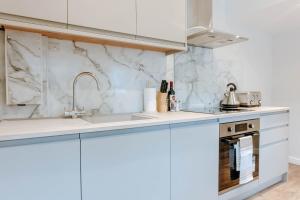 a kitchen with white cabinets and a sink at Mayfield Two - Central Harrogate Apartment in Harrogate
