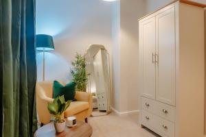 a living room with a chair and a mirror at Mayfield Two - Central Harrogate Apartment in Harrogate