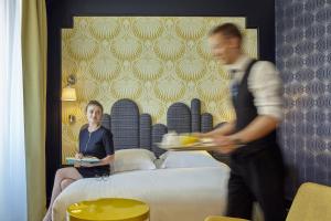 un homme et une femme dans une chambre d'hôtel avec des assiettes de nourriture dans l'établissement Grand Hôtel du Midi Montpellier - Opéra Comédie, à Montpellier