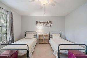 two beds in a white room with a ceiling fan at Townhome - Convenient Location in Houston