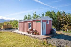 a small red shed with a deck in a field at Sólvellir Holiday Home in Kjósahreppur