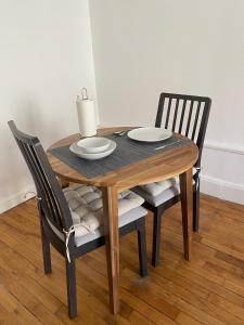 - une table en bois avec deux chaises et une table avec des assiettes dans l'établissement Appart hyper-centre, à 5 min à pieds de la gare, à Longwy