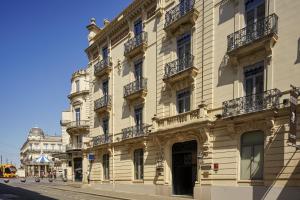 - un grand bâtiment avec balcon dans une rue de la ville dans l'établissement Grand Hôtel du Midi Montpellier - Opéra Comédie, à Montpellier