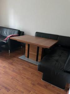 drewniany stół i skórzana kanapa w pokoju w obiekcie Apartment Lara w mieście Friedrichshafen
