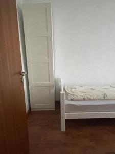 biały pokój z łóżkiem i otwartymi drzwiami w obiekcie Apartment Lara w mieście Friedrichshafen