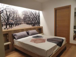 1 dormitorio con 1 cama con una pintura en la pared en Le stagioni della vita, en Bovino
