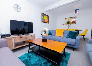 a living room with a blue couch and a tv at Wandle Grove House in Birmingham