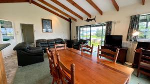 a living room with a wooden table and a tv at Castlepoint Holiday Park & Motels in Castlepoint