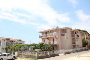 a pink apartment building with a white car parked in front at Apartments Petricevic in Sutomore