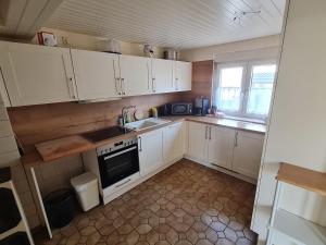 a kitchen with white cabinets and a stove and a window at Ferienwohnung im Wispertaunus in Dickschied