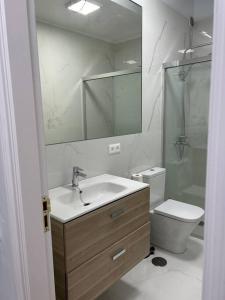 a bathroom with a sink and a toilet and a mirror at Moderno apartamento cerca al mar in Tías