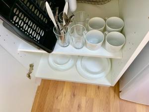 a white shelf with cups and utensils on it at London Studio Apartments Close to Station NP2 in London