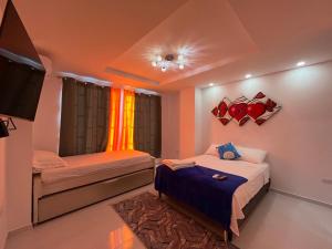 a bedroom with two beds and a flat screen tv at Hotel Boutique Al-Basit in Cartagena de Indias