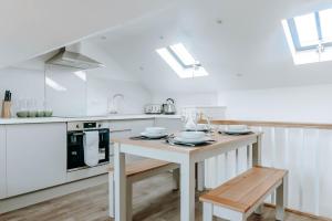 a white kitchen with a table and a stove at Mayfield Three - Central Harrogate Apartment in Harrogate +26 photos