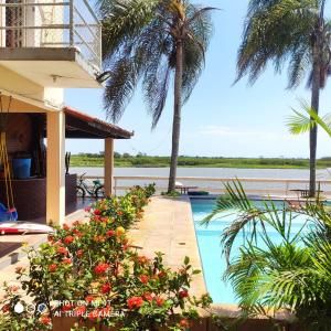 a resort with a swimming pool and palm trees at Pousada Sobre as Águas in São João da Barra