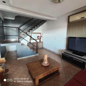 a living room with a staircase and a television at Pousada Sobre as Águas in São João da Barra