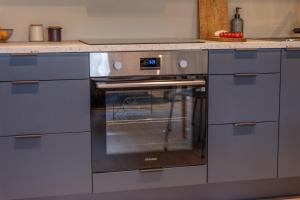 a stainless steel oven in a kitchen with blue cabinets at Elegant apartment in city centre in Tromsø +13 photos