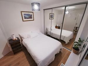 Peaceful house in the heart of Glasgow city, close to Queen Elizabeth Hospital and Govan subway, Free Private Parking في غلاسكو: غرفة نوم صغيرة بسريرين ومرآة