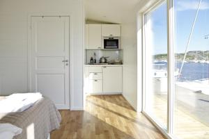 a white bedroom with a kitchen and a large window at Kajkanten Vrångö in Vrångö