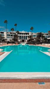 a large pool with blue water in front of a building at RockBeach bungalow in Costa Teguise