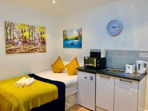 a room with two beds and a kitchen with a sink at London Studio Apartments Close to Station NP4 in London