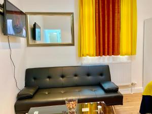 een woonkamer met een bank en een spiegel bij London Studio Apartments Close to Station NP4 in Londen