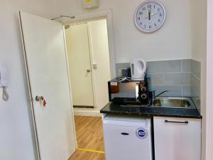 une cuisine avec un évier et une horloge murale dans l'établissement London Studio Apartments Close to Station NP5, à Londres