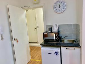 a kitchen with a sink and a clock on the wall at London Studio Apartments Close to Station NP5 in London