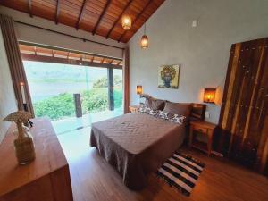 a bedroom with a bed and a large window at Casa do Lago Lapinha da Serra in Santana do Riacho
