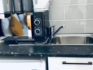 a kitchen counter with a sink and a microwave at London Studio Apartments Close to Station NP4 in London