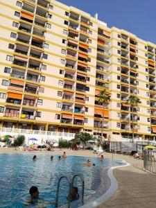 a group of people in a swimming pool next to a large building at Los Cristianos Achacay Appartement standing Vue panoramique in Los Cristianos
