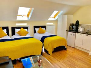 two beds in a room with yellow pillows at London Studio Apartments Close to Station NP7 in London