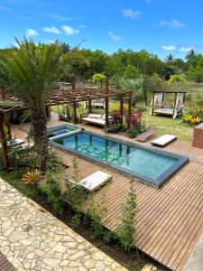 un patio trasero con piscina y terraza de madera en Barong EcoVilla, en Barra Grande