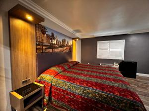 1 dormitorio con 1 cama con una manta colorida en The Patio Motel - Los Angeles, LAX, en Gardena
