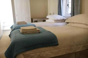 two beds with towels on top of them in a bedroom at Travershes Holiday Cottage in Exmouth