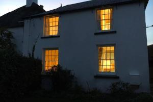 ein weißes Haus mit Lichtern in den Fenstern in der Unterkunft Travershes Holiday Cottage in Exmouth