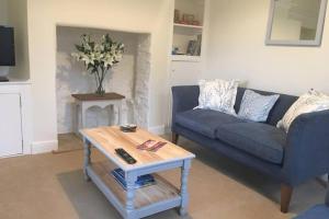 uma sala de estar com um sofá azul e uma mesa de centro em Travershes Holiday Cottage em Exmouth