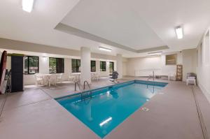 a swimming pool with chairs and a table in a building at Sleep Inn Northlake in Charlotte