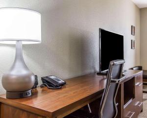 a desk with a lamp a phone and a television at Comfort Suites West Omaha in Omaha