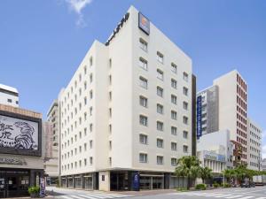 a white building with a clock on top of it at Comfort Hotel Naha Prefectural Office in Naha