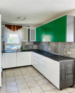 una cocina con armarios blancos y verdes y una ventana en Ferienhaus JoNa - 4 Zimmer & 2 Bäder en Oberwesel