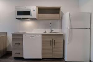 La cuisine est équipée d'un réfrigérateur blanc et d'un four micro-ondes. dans l'établissement WoodSpring Suites Detroit Sterling Heights, à Sterling Heights