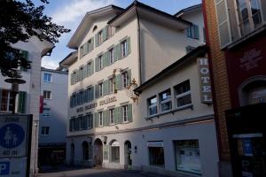 a white building with green windows on a street at Hotel Restaurant Goldener Schlüssel in Altdorf