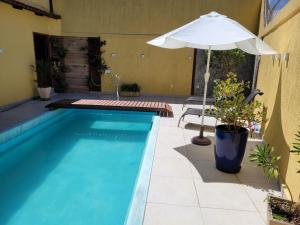 uma piscina com um guarda-sol e uma mesa e uma cadeira e um guarda-sol em Loft da Beth na serra em Petrópolis