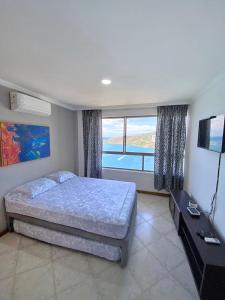 a bedroom with a bed and a large window at Espectacular vista a la playa el Rodadero in Santa Marta